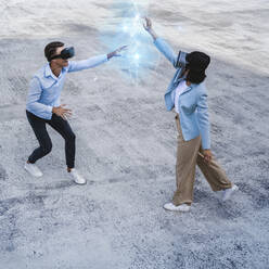 Freunde benutzen gemeinsam Virtual-Reality-Headsets auf dem Fußweg - UUF25294
