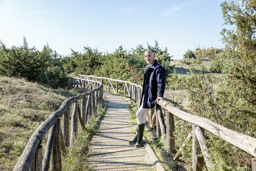 Man leaning on railing at wooden bridge - EIF02801