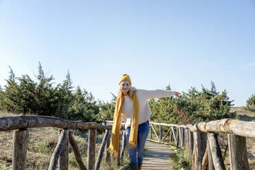 Carefree woman dancing on wooden bridge - EIF02806