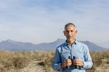 Man with binoculars at dunes - EIF02811