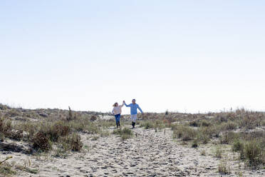 Glückliches Paar läuft auf Sand und genießt das sonnige Wochenende - EIF02835