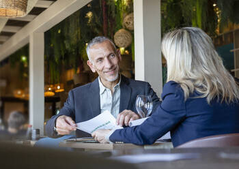 Geschäftsmann zeigt einem Kunden ein Dokument bei einem Treffen im Restaurant - EIF02838