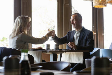 Couple toasting champagne glasses at lunch date in restaurant - EIF02846