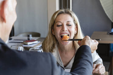 Mann füttert Frau beim Mittagessen im Restaurant mit Stäbchen mit Sushi - EIF02851