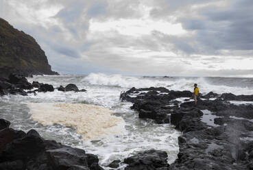 Mann steht auf Felsen in der Nähe des Thermalbeckens von Ponta da Ferraria, San Miguel, Azoren, Portugal - WWF05939