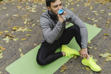 Athlete drinking water on exercise mat - SEAF00248