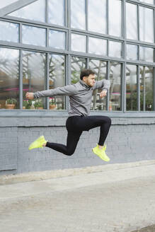 Dedicated young man jumping and exercising outside greenhouse - SEAF00251