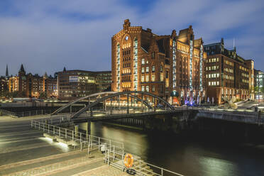 Germany, Hamburg, Bridge over canal in Speicherstadt district at dusk - KEBF02107