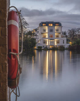 Deutschland, Hamburg, Alster City Garden Villa in der Abenddämmerung mit Rettungsring im Vordergrund - KEBF02111