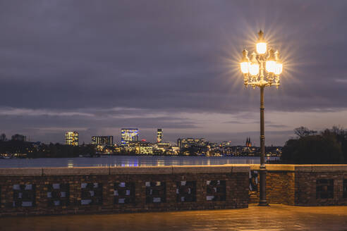 Deutschland, Hamburg, Skyline der Stadt von der Krugkoppelbrücke aus gesehen bei Nacht mit leuchtenden Straßenlaternen im Vordergrund - KEBF02112