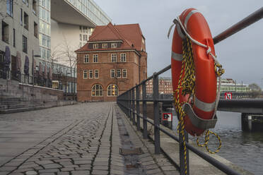 Deutschland, Hamburg, HafenCity mit hängendem Rettungsring im Vordergrund und altem Zollamt im Hintergrund - KEBF02113