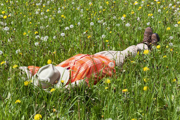 Man sleeping on grass with hat over face at meadow - GWF07287