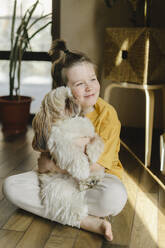 Smiling boy embracing dog at home - SEAF00255