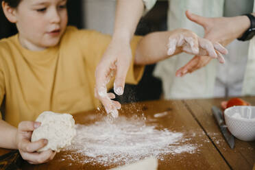 Mother helping son to knead dough on table - SEAF00260