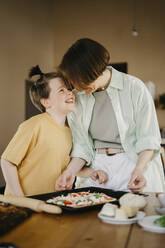 Happy son looking at mother preparing pizza together - SEAF00280