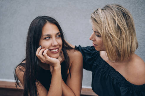 Young woman with hand on chin looking at friend - OMIF00275