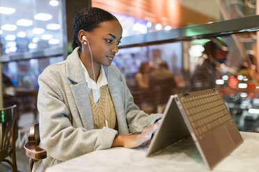 Mädchen mit Touchscreen-Laptop im Café - JRVF02338
