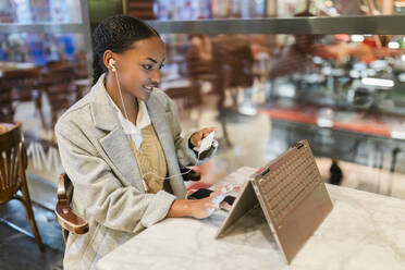 Mädchen macht Online-Zahlung per Kreditkarte auf Touchscreen-Laptop im Café - JRVF02341