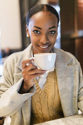 Lächelndes Mädchen trinkt Kaffee im Cafe - JRVF02350