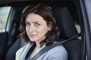 Smiling woman sitting on driver seat in electric car - ZEDF04324