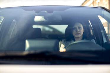 Woman driving electric car seen through windshield - ZEDF04327