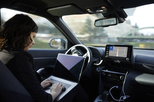 Businesswoman with laptop working in driverless car - ZEDF04333