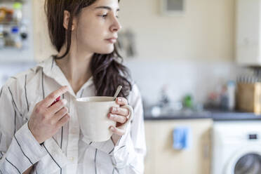 Junge Frau hält Teetasse in der Küche zu Hause - WPEF05632