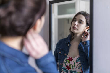 Young woman looking in mirror at home - WPEF05638