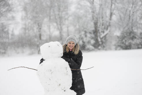 Smiling woman with snowman at winter park - CHPF00819