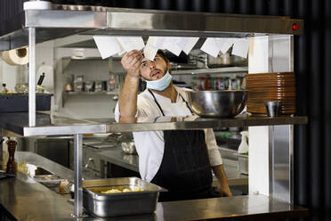 Koch mit Schutzmaske bei der Kontrolle eines Karteninhabers im Restaurant - IFRF01335