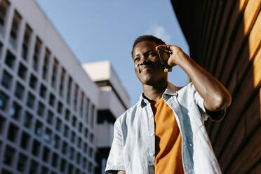 Smiling man talking on smart phone in city at sunset - TCEF02138