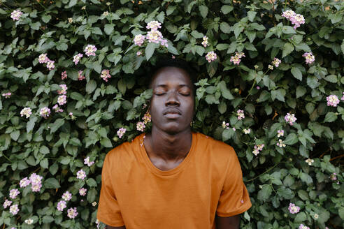 Young man with eyes closed relaxing amidst plants - TCEF02146