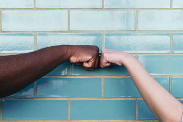 Mann und Frau geben Faustschlag auf türkisfarbene Backsteinwand - ASGF02028