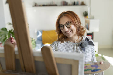 Smiling woman painting at home - JCCMF04837