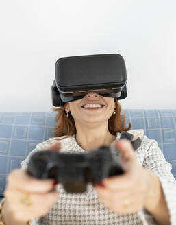 Frau spielt zu Hause ein Spiel mit einem Virtual-Reality-Headset - JCCMF04842