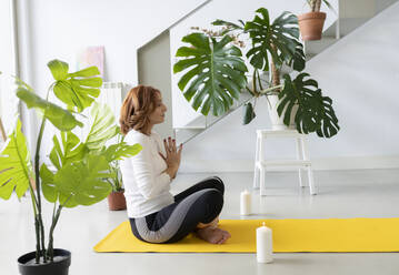 Frau übt Yoga auf einer Übungsmatte zu Hause - JCCMF04852