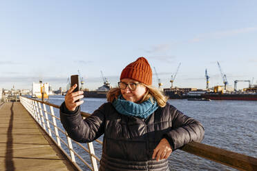 Ältere Frau nimmt Selfie durch Smartphone am Hafen - IHF00734