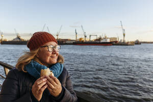 Ältere Frau mit Sandwich und Blick auf die Elbe - IHF00737