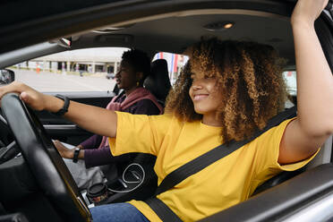 Young woman driving car with friend on road trip - VYF00780