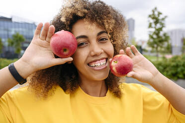 Glückliche junge Frau mit Äpfeln in der Hand - VYF00786