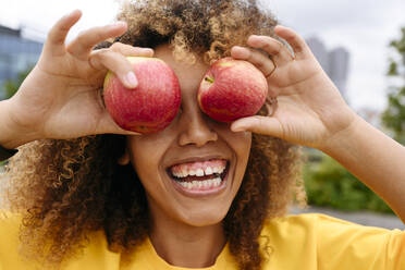 Fröhliche Frau, die ihre Augen mit Äpfeln bedeckt - VYF00787