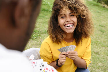 Frau lachend und Karten spielend mit Freund im Park - VYF00833