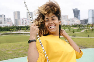 Happy woman playing on swing in park - VYF00837