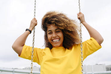 Smiling woman on swing in front of clear sky - VYF00844