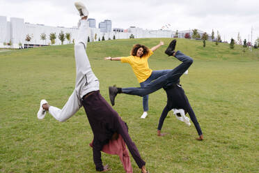 Carefree young men doing cartwheel by friend in park - VYF00847