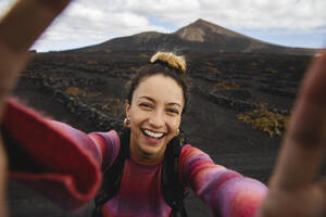 Glückliche Frau nimmt Selfie mit malerischen Landschaft im Hintergrund - MRAF00806