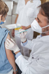 Doctor administering vaccine to boy at vaccination center - MFF08347