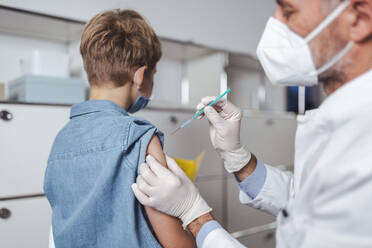 Mitarbeiter des Gesundheitswesens verabreichen einem Jungen den COVID-19-Impfstoff im Impfzentrum - MFF08369