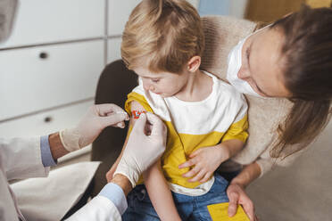 Boy getting bandage by doctor after vaccination at center - MFF08388