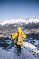 Man wearing yellow jacket hiking downhill mountains - OMIF00321